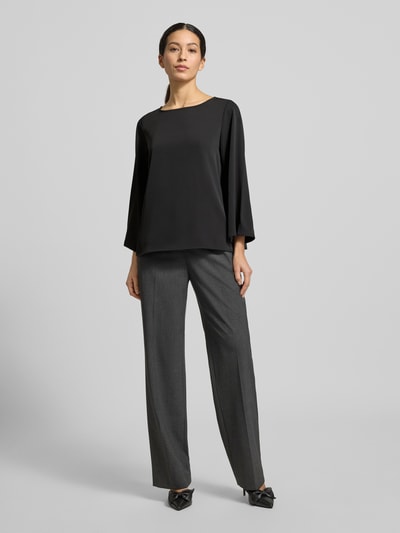 Modelka kobieca nosi Blusenshirt mit Rundhalsausschnitt od comma, czarny materiał z domieszką stretchu, luźny krój, całkowita długość tyłu 59 cm, długość rękawa 52 cm, widok całej sylwetki z przodu.