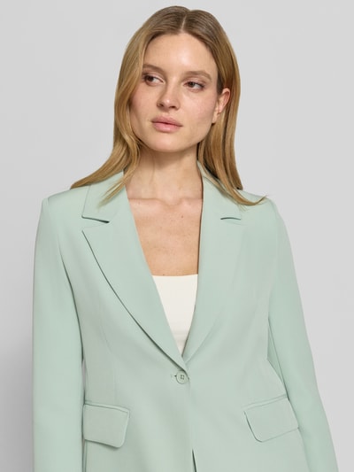 Vrouwenmodel draagt blazer met klepzakken model 'Isa' van GUIDO MARIA KRETSCHMER WOMAN in mintgroene materiaalmix met stretch, recht model, reverskraag, knoopsluiting, detailopname bovenlichaam.
