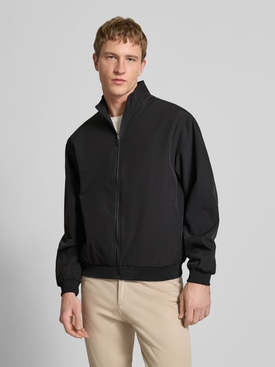 Mannelijk model draagt Regular fit jack met opstaande kraag model 'Charge' van JACK & JONES, zwart, steekzakken, ritssluiting, elastische boorden, ganzekörperaanzicht van voren. Ruglengte bij maat M: 66 cm, schouderbreedte: 49 cm, borstwijdte: 50 cm, mouwlengte: 64 cm.