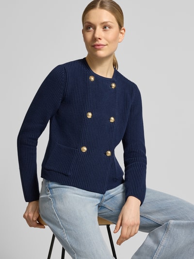 Frauenmodel trägt Regular Fit Strickjacke aus reiner Baumwolle von Lauren Ralph Lauren in Strickoptik, Dunkelblau mit goldenen Knöpfen, aufgesetzte Seitentasche, Langarm, Rundhals, Materialverarbeitung Strick, Nahaufnahme Oberkörper.