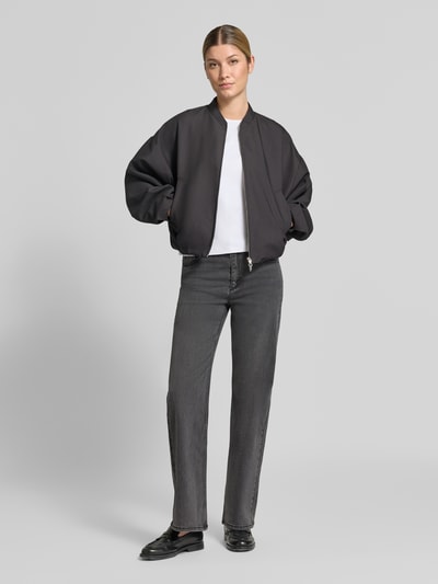 Frauenmodel trägt Wide Leg Jeans im 5-Pocket-Design von Christian Berg Woman in Grau, kombiniert mit schwarzer Jacke und weißem Shirt, elastischer Baumwoll-Mix mit Viskose-Anteil, Ganzkörperansicht von vorne.