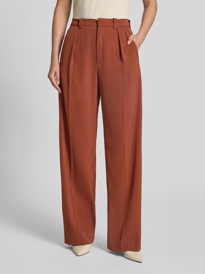 Frauenmodel trägt Bundfaltenhose mit Gesäßtaschen Modell 'ADUCT' von DRYKORN, rostbraun, glatte Textur, Regular Fit, Nahaufnahme Oberkörper.