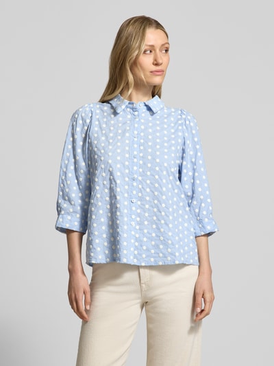 Frauenmodel trägt Regular Fit Bluse im Allover-Look Modell 'Bono' von LOLLYS LAUNDRY, reine Baumwolle, hellblau mit weißen Punkten, Hemdblusenkragen, Knopfleiste, 3/4-Arm, glatte Struktur, Ganzkörperansicht von vorne.