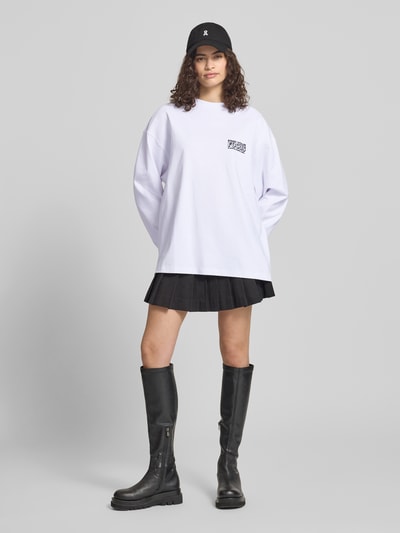 Frauenmodel trägt Oversized Longsleeve mit Statement-Print von Karo Kauer in Weiß, kombiniert mit schwarzem Rock, reine Baumwolle, Rundhalsausschnitt, Ganzkörperansicht von vorne.