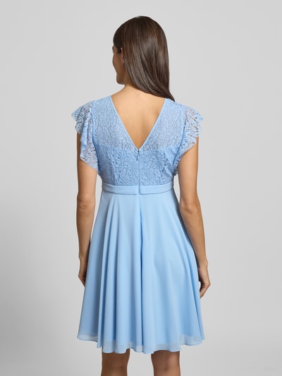 Frauenmodel trägt Knielanges Cocktailkleid mit Rundhalsausschnitt von Jake*s Cocktail in Hellblau, taillierter Schnitt, blickdichtes Unterkleid, Nahtreißverschluss, Knielänge, Rückenlänge 90 cm, Brustweite 35 cm, Ärmellänge 10 cm, Ganzkörperansicht Rückansicht.