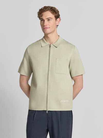 Męski model nosi koszulkę polo Slim Fit Poloshirt mit Zweiwege-Reißverschluss Modell 'RICO' von Samsøe Samsøe, mieszanka wiskozy z dodatkiem streczu, krój slim fit, zamek błyskawiczny dwustronny, brustasza, długość tyłu w rozmiarze M: 67 cm, jasny beż, prosty krój, gładka faktura, Ganzkörperansicht von vorne.