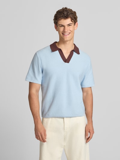 Männermodel trägt Regular Fit Poloshirt mit V-Ausschnitt Modell 'COTEDAZUR' von Jack & Jones aus reiner Baumwolle, hellblau mit braunem Kragen, Label-Detail, Rückenlänge bei Größe M 67 cm, Ganzkörperansicht von vorne.