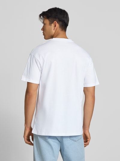 Męski model trägt Regular Fit T-Shirt mit Motiv-Print Modell 'Road Side Snack' von Carhartt Work In Progress z bawełny, okrągły dekolt, długość tyłu w rozmiarze M: 72 cm, jasne kolory, prosta forma, gładka tekstura, Ganzkörperansicht Rückansicht.