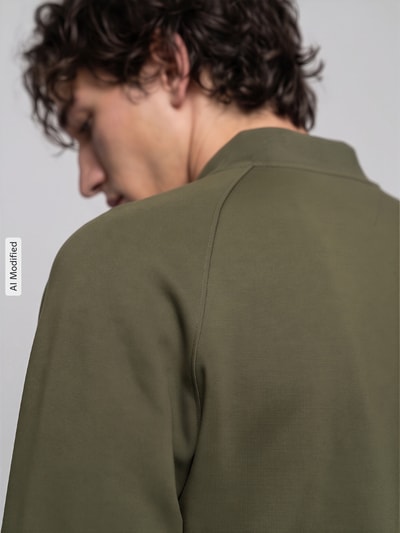 Männermodel trägt Regular Fit Sweatjacke aus Baumwoll-Mix von Tommy Hilfiger in Olivgrün, glatte Struktur, Ganzkörperansicht Rückansicht, KI-modifiziertes Bild.