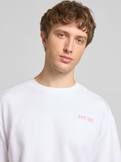 Männermodel trägt Regular Fit T-Shirt aus reiner Baumwolle Modell 'CASPIAN AIRFLEX AMORE' von Only & Sons, Weiß, Motiv-Print, Nahaufnahme Oberkörper. Atmungsaktiv, feuchtigkeitsregulierend, Optik: Unifarben, Rundhals, Kurzarm.