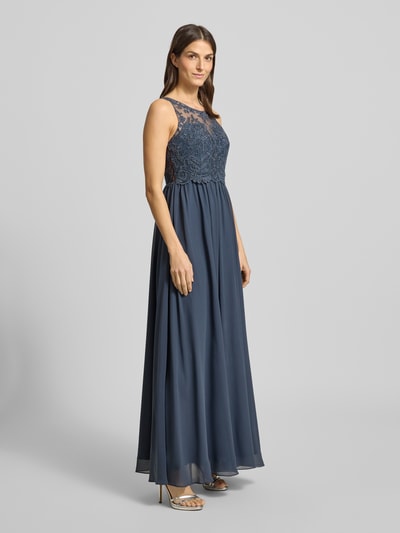 Frauenmodel trägt Regular Fit Abendkleid mit floralem Spitzenbesatz von Laona, semitransparenter floraler Spitzenbesatz, Ziersteinbesatz, ärmelloses Design, blickdichter Unterrock, dunkles Blau, fließender Stoff, Ganzkörperansicht von vorne.