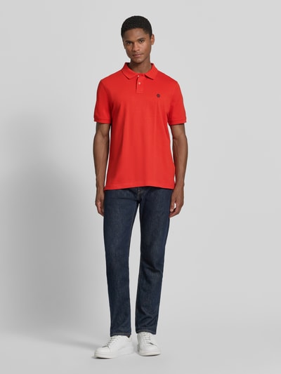 Männermodel trägt Slim Fit Poloshirt mit Label-Stitching von MCNEAL in Rot aus Reine Baumwolle mit Knopfleiste, Ganzkörperansicht von vorne. Rückenlänge bei Größe M 72 cm.