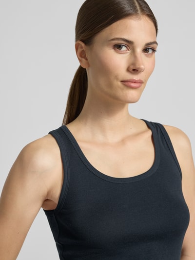 Modelka kobieca nosi top Tanktop mit Rundhalsausschnitt von Lanius z czystej bawełny, krój slim fit, okrągły dekolt, długość tyłu w rozmiarze 36: 55 cm, kolor ciemny, gładka tekstura. Zbliżenie górnej części ciała z przodu.