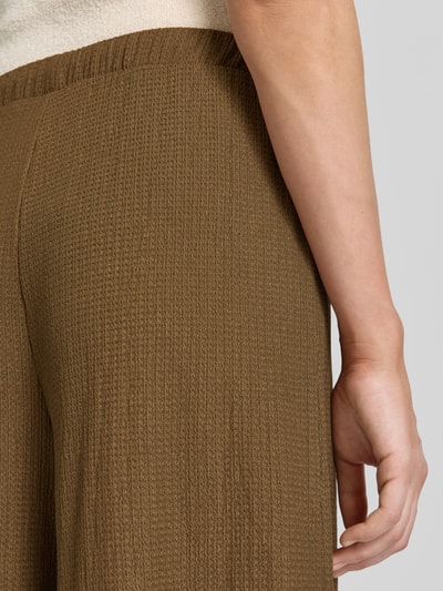 Frauenmodel trägt Loose Fit Hose in Crinkle-Optik von s.Oliver RED LABEL in Braun mit strukturierter Oberfläche, Nahaufnahme Hüfte.