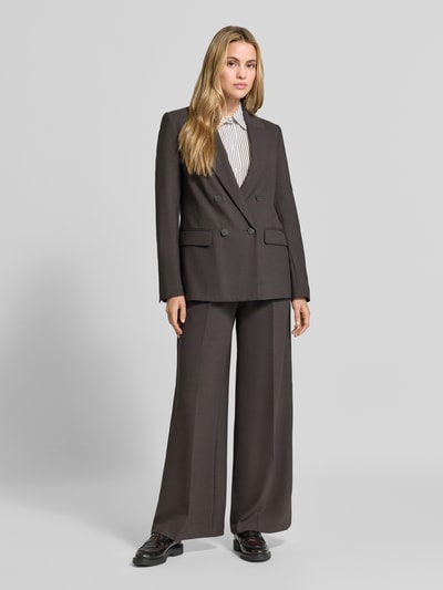 Frauenmodel trägt Wide Fit Hose aus Viskose-Mix von comma in Dunkelbraun mit Bundfalten und Gesäßtaschen, Ganzkörperansicht von vorne.