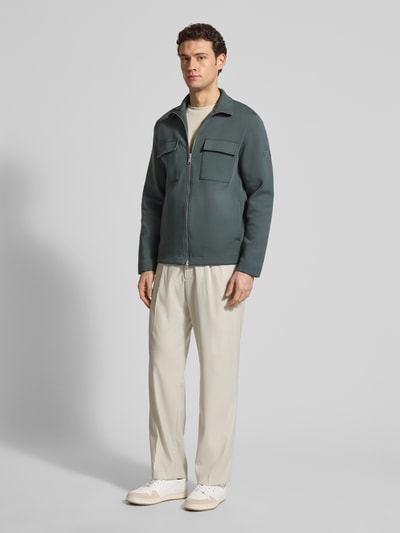Mężczyzna model nosi Regular Fit Sweatjacke aus Baumwoll-Mix od Marc O'Polo, kolor jednolity, kieszenie na piersi, długi rękaw, bawełna-mix, stehkraag, zamek dwukierunkowy, łatka z logo, faktura scuba, widok całej sylwetki z przodu.