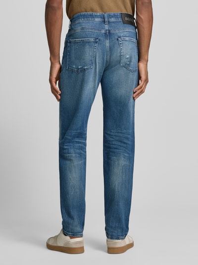 Männermodel trägt Regular Fit Straight Leg Jeans aus Baumwoll-Mix Modell 'RE.MAINE BO VISIBLE' von BOSS Orange, Used-Look, unifarben, Label-Stitching-Applikation, 5-Pocket-Design, Denim-Material, Ganzkörperansicht Rückansicht.