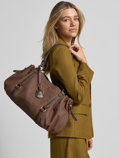 Kobiece modelka prezentuje Tote Bag z detalem z logo model 'GINESA' od Liu Jo White, kolor brązowy, główna przegroda z zapięciem na magnes, smukłe paski na ramię, Szerokość w rozmiarze 1: 34 cm, długość w rozmiarze 1: 27 cm, głębokość w rozmiarze 1: 22 cm, długość paska na ramię w rozmiarze 1: 66 cm, ujęcie całej sylwetki z przodu.