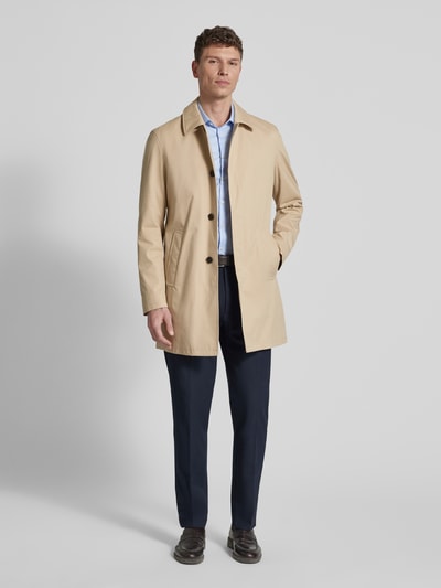Męski model nosi Kurzmantel mit Eingrifftaschen od bugatti, kremowy kolor, bawełniany mix ze stretchem, krój regular fit, umieszczone kieszenie, długość tyłu w rozmiarze 50 to 90 cm, szerokość ramion w rozmiarze 50 to 46 cm, szerokość klatki piersiowej w rozmiarze 50 to 57 cm, długość rękawa w rozmiarze 50 to 66 cm, widok na całe ciało z przodu.
