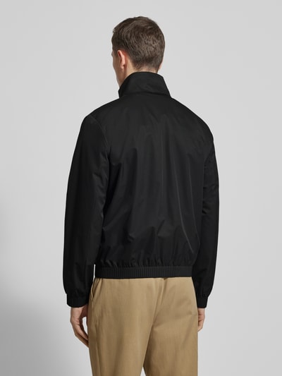 Männermodel trägt schwarze Jacke mit Stehkragen und Reißverschluss von CK Calvin Klein, Regular Fit, Rückenansicht, Ganzkörperansicht Rückansicht.