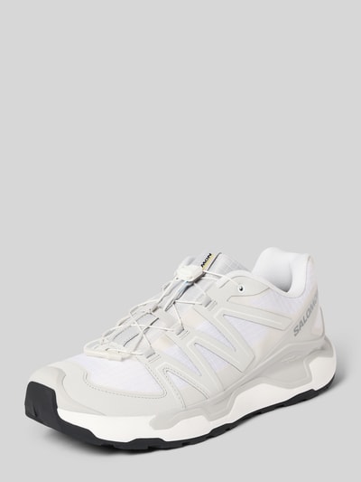 Produktfoto, weiß-grauer Sneaker mit profilierter Sohle Modell 'XC ROAM' von Salomon, abgerundete Spitze, Schnürung, Logo auf der Seite.