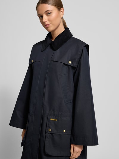 Frauenmodel trägt Regular Fit Mantel aus Baumwoll-Mix von Barbour in Dunkelblau mit Umlegekragen und aufgesetzten Taschen, Nahaufnahme Oberkörper.