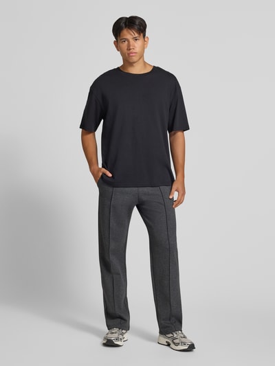 Mężczyzna model nosi spodnie dresowe Straight Fit Sweatpants mit elastischem Bund od REVIEW, Mieszanka materiałów z mieszanką bawełny, krój straight fit, elastyczny pas, kanty, szerokość w rozmiarze M: 42 cm, długość wewnętrzna nogawki w rozmiarze M: 82 cm, kolor szary melanż, proste nogawki, gładka faktura, widok całej sylwetki z przodu.