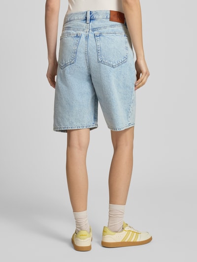 Frauenmodel trägt Jeansshorts mit Label-Detail von Calvin Klein Jeans in hellem Used-Look, Reine Baumwolle, Regular-Fit, Eingrifftaschen, Bundweite 41 cm, Innenbeinlänge 24 cm, Ganzkörperansicht Rückansicht.