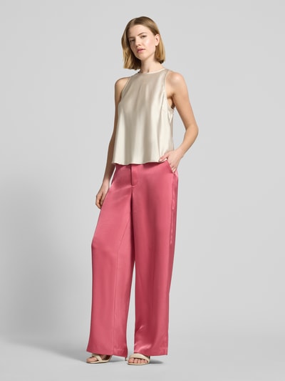 Frauenmodel trägt Satinhose mit angedeuteten Gesäßleistentaschen Modell 'Emmett' von Neo Noir, Satin, Wide-Fit, rosa, Eingrifftaschen, Haken- und Reißverschluss, Bundweite 39 cm, Innenbeinlänge 86 cm, Ganzkörperansicht von vorne.