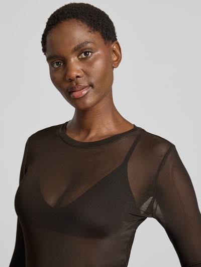 Frauenmodel trägt Slim Fit Langarmshirt mit Rundhalsausschnitt Modell 'LOVA' von VERO MODA, transparentes Schwarz, Nahaufnahme Oberkörper.