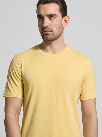 Männermodel trägt T-shirt mit labeldetail van bugatti in lichtgeel, puur katoen, recht model, ronde hals, ruglengte maat M 69 cm, nahaufnahme oberkörper.