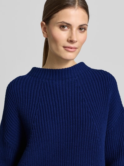 Frauenmodel trägt Strickpullover mit Stehkragen Modell 'TELLINA' von Someday in Dunkelblau, grob gestrickt, Nahaufnahme Oberkörper. Lockerer Schnitt, Baumwoll-Mix, gerippte Abschlüsse.