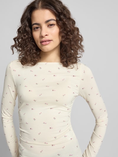 Frauenmodel trägt Longsleeve mit Viskose-Anteil von OH APRIL, cremefarben mit feinem Blumenmuster, körpernaher Schnitt, Nahaufnahme Oberkörper.
