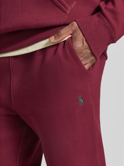 Männermodel trägt Relaxed Fit Sweathose aus Baumwoll-Mix von Polo Ralph Lauren in Dunkelrot mit glatter Struktur, Nahaufnahme Hüfte, Herren Sweathose von Polo Ralph Lauren