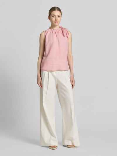 Frauenmodel trägt Regular Fit Bluse aus Viskose-Mix mit Leinen-Anteil von Christian Berg Woman in Rosa mit Zierschleife, Stehkragen mit Rüschenbesatz und Ärmelloses-Design, materialtypische glatte Textur, Rückenlänge bei Größe 36: 54 cm, Ganzkörperansicht von vorne.