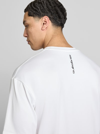 Männermodel trägt T-Shirt mit Rundhalsausschnitt und Logo von Quiksilver im Material-Mix mit Stretch-Anteil, Regular-Fit, Rückenlänge 75 cm, Nahaufnahme Rückansicht.