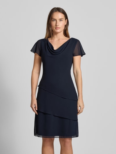 Modelka kobieca nosi tailliertes Cocktailkleid mit Volants von Christian Berg Cocktail w kolorze granatowym, z wodospadowym dekoltem i krótkimi rękawami z falbanami, dopasowany fason, z bocznym zamkiem, długość do kolan, prosty materiał, całkowity widok z przodu.