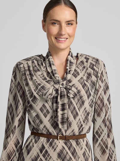 Vrouwenmodel draagt Tailliertes vrijetijdsjurk met all-over motief van Jake*s Collection in beige en zwart, detailopname bovenlichaam.