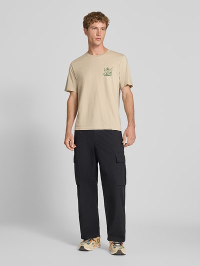 Męski model nosi Regular Fit T-Shirt aus reiner Baumwolle Model 'BREWY' od JACK & JONES, nadruk z napisem, beżowy, Długość tyłu w rozmiarze M: 68 cm, Ganzkörperansicht von vorne