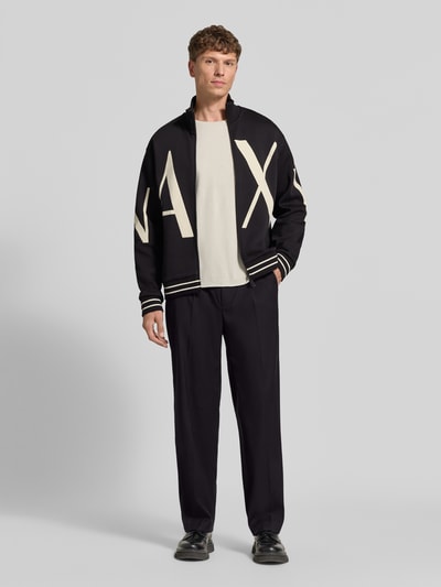 Männermodel trägt Sweatjacke aus Baumwoll-Mix von Armani Exchange in Schwarz mit Label-Print, lockere Passform, Ganzkörperansicht von vorne