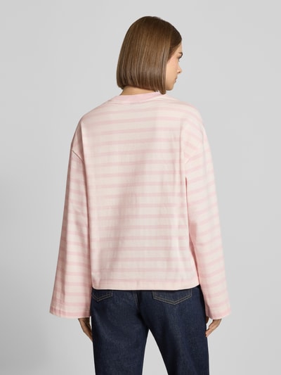 Kobiece model nosi Relaxed Fit Langarmshirt aus reiner Baumwolle od Gina Tricot, jasnoróżowe paski, okrągły dekolt, długość tyłu 62 cm, bawełna, krój relaxed fit, widok całej sylwetki z tyłu.