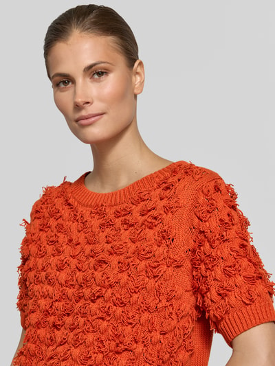 Frauenmodel trägt Strickpullover mit Rundhalsausschnitt und 1/2-Arm von Oui aus Reine Baumwolle in leuchtendem Orange, Nahaufnahme Oberkörper.