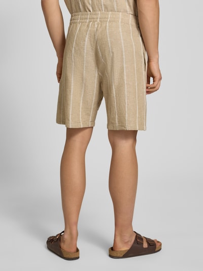 Männermodel trägt Leinenshorts mit Logo-Stitching von REVIEW, beige mit weißen Streifen, Baumwoll-Mix, elastischer Bund, Ganzkörperansicht Rückansicht.