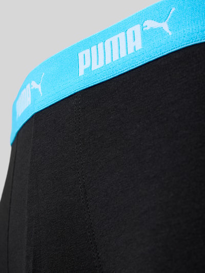 Produktfoto, Trunks im 4er-Pack mit elastischem Logo-Bund von PUMA aus schwarzem Baumwoll-Mix mit Stretch-Anteil, körpernaher Schnitt, blauer Elastischer-Logo-Bund, glatte Struktur