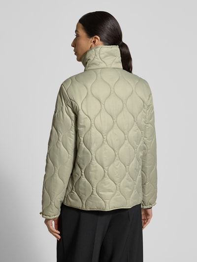 Modelka nosi Regular Fit Steppjacke mit gefüttertem Stehkragen od Christian Berg Woman Selection, steppowana tekstura, beżowy kolor, krój regular fit, ocieplony kołnierz, kieszenie z przodu, pełna listwa guzikowa, długość tyłu w rozmiarze 36: 62 cm, szerokość ramion w rozmiarze 36: 41 cm, szerokość klatki piersiowej w rozmiarze 36: 52 cm, długość rękawa w rozmiarze 36: 62 cm, widok całej sylwetki z tyłu