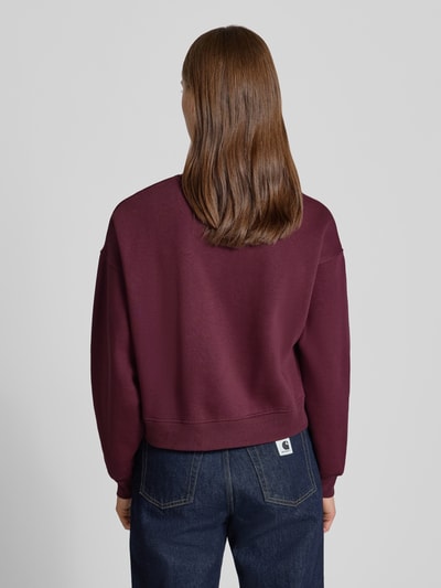 Vrouwenmodel draagt Relaxed Fit Sweatshirt uit katoenmix Model 'Tatum' van JJXX in bordeaux met ribboordjes, met lange mouwen en statementpatch, ronde hals, schouderpartij met verlaagde schoudernaden, dames sweatshirt, katoenmix, relaxed fit, detailopname rugaanzicht.