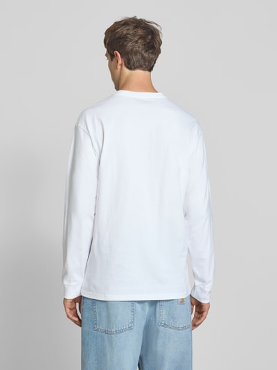 Männermodel trägt Longsleeve mit Label-Stitching von Carhartt Work In Progress in Weiß, Relaxed Fit, reine Baumwolle, Ganzkörperansicht Rückansicht.