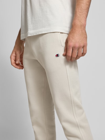 Männermodel trägt Sweatpants mit elastischem Bund und Label-Stitching von CHAMPION in Beige, Baumwoll-Mix, Regular-Fit, Nahaufnahme Oberkörper.