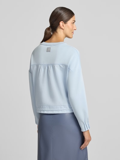 Frauenmodel trägt Sweatshirt aus Viskose-Mix von Marc Cain in hellblau, lockere Passform, Strickbesatz mit Streifenmuster, Tunnelzug am Bund, gerippter Rundhalsausschnitt, Ganzkörperansicht Rückansicht.