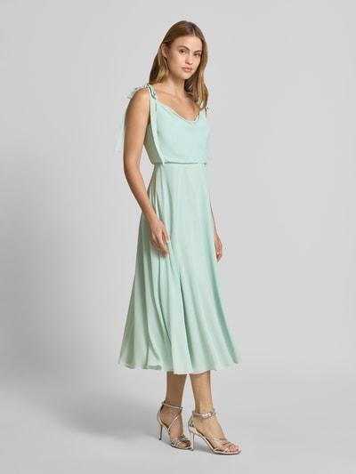 Frauenmodel trägt Knielanges Cocktailkleid mit Zierschleifen von Jake*s Cocktail in Mint, taillierte Passform, blickdichter Unterrock, Ärmelloses-Design, fließende Textur, Ganzkörperansicht von vorne.